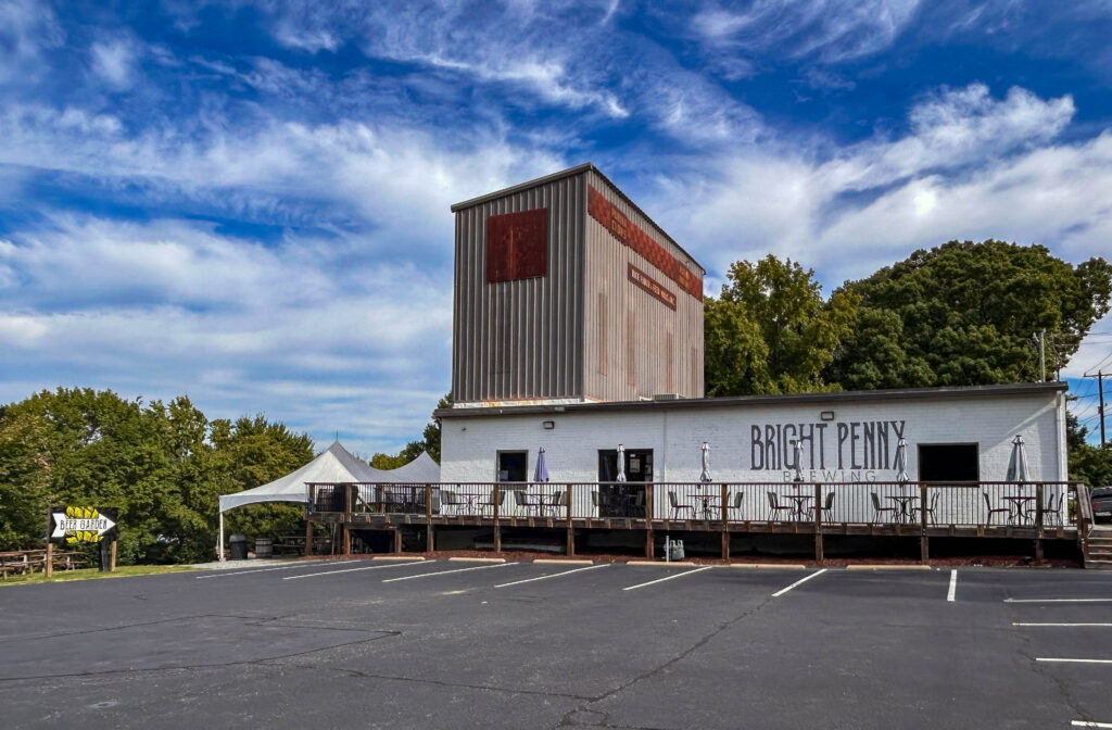 Outdoor view of Bright Penny Brewing surrounding by trees and bright blue skies