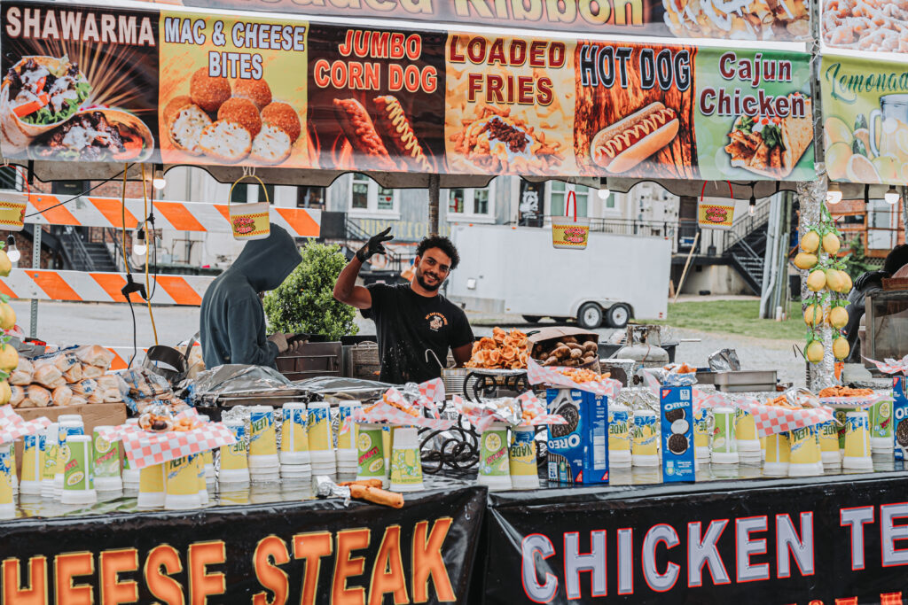 image of a food vendor stand with worker waving to the camera 